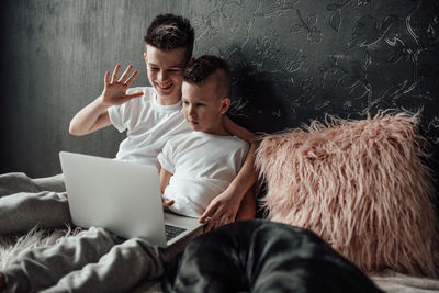 Young man using mobile phone while relaxing on bed at home