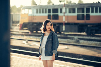 Young woman standing at railroad station