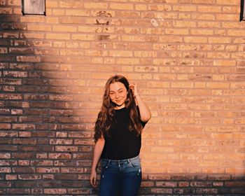 Full length of woman standing against brick wall