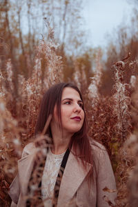 Portrait of young woman standing by grass