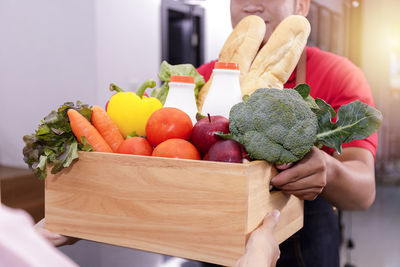 Midsection of person holding vegetables on table