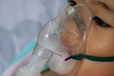 Close-up of girl wearing oxygen mask