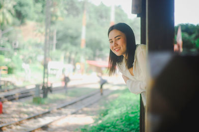 Smiling woman standing against railroad track