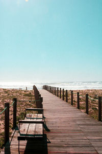 Wooden pier on sea against clear sky