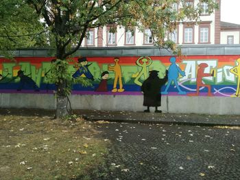 Full length of woman against graffiti wall in city