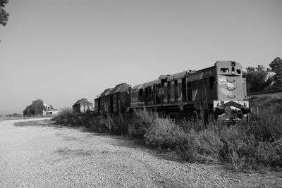 Abandoned train on field against clear sky