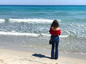 Full length rear view of woman standing on beach
