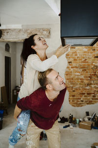 Happy couple fixing lighting equipment while renovating home