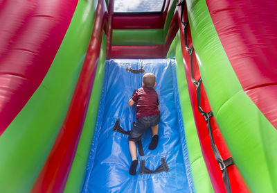 High angle view of boy playing on colorful bouncy castle