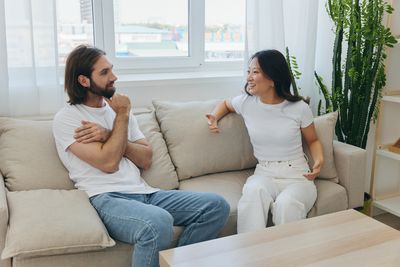 Couple using laptop while sitting on sofa at home