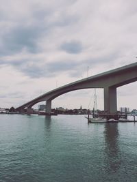 View of suspension bridge over sea against cloudy sky