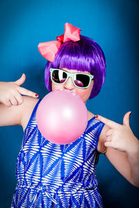 Low section of woman with pink balloons against blue background