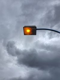 Low angle view of illuminated street light against cloudy sky