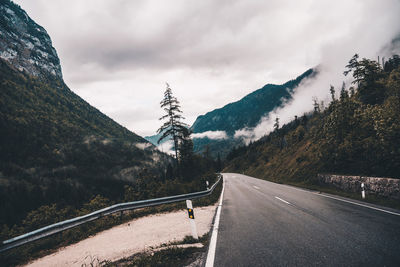 Road by mountains against sky during winter