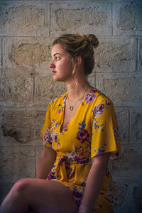 Beautiful young woman standing against yellow wall