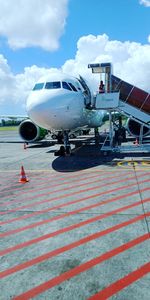 Airplane on airport runway against sky