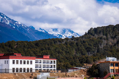 Buildings by mountains against sky