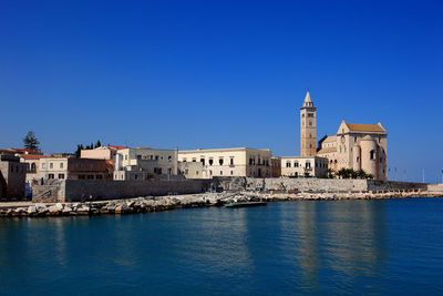 Buildings in front of sea against clear blue sky