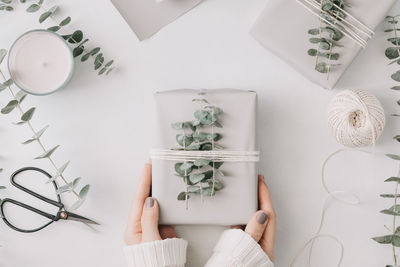 Directly above shot of woman holding gift box on table