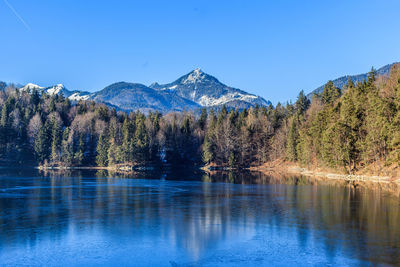 Scenic view of lake and mountains against clear blue sky