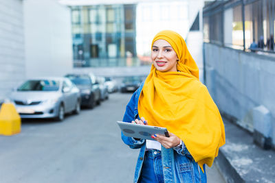 Portrait of young woman standing in city