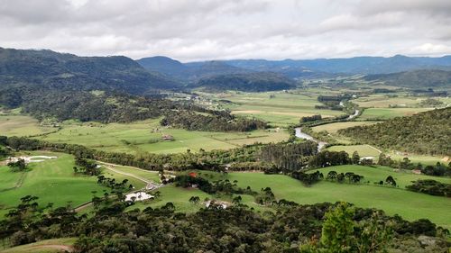 High angle view of green landscape and mountains against sky