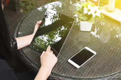 Low section of person using mobile phone on table