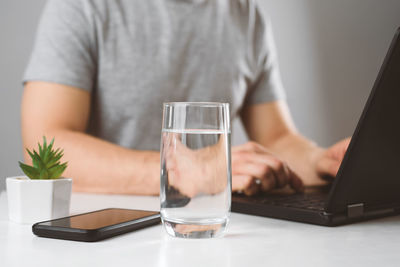 Midsection of man using mobile phone on table