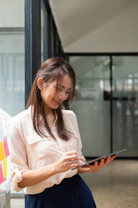 Young woman using mobile phone while standing in train