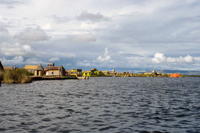 Buildings by sea against sky