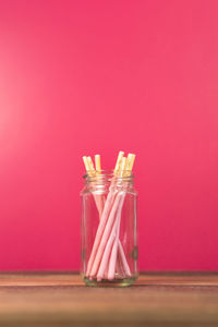 Glass of jar on table against red background