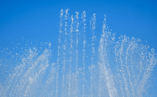 Low angle view of fireworks against blue sky on sunny day