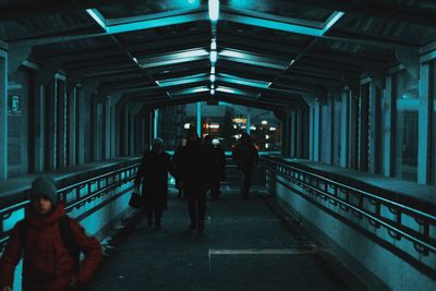 People walking on illuminated bridge