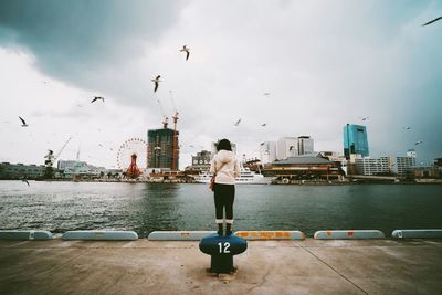 Woman standing on bollard on city pier