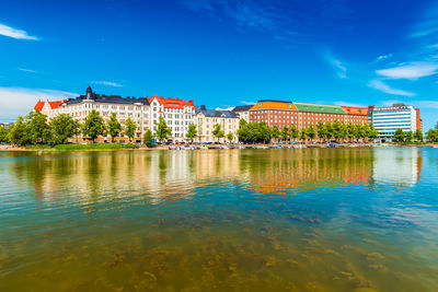 Buildings by river against sky