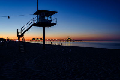Lifeguard hut on beach against clear sky at sunset