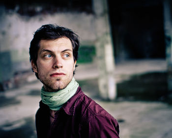 Close-up of mid adult man looking away in abandoned building