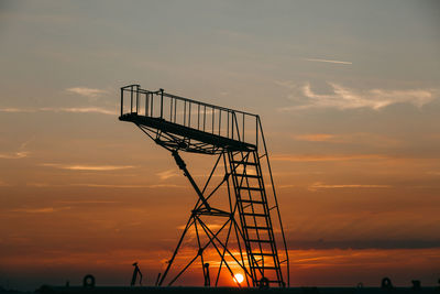 Silhouette gangway against sky during sunset