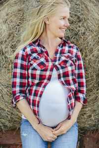 Pregnant woman leaning on haybale