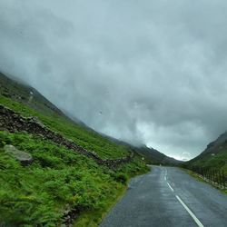 Country road against cloudy sky