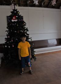 Full length of boy standing by christmas tree