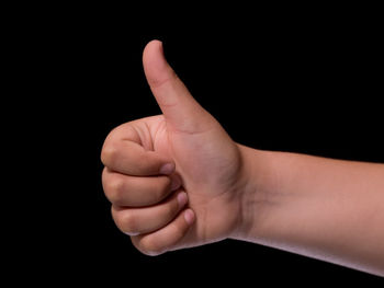 Close-up of hand gesturing against black background