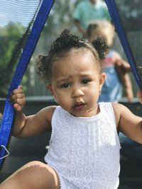 Portrait of cute girl sitting on swing at playground