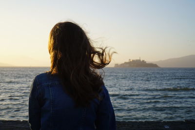 Rear view of woman looking at sea against sky