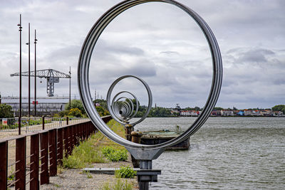 Ferris wheel by river against sky in city