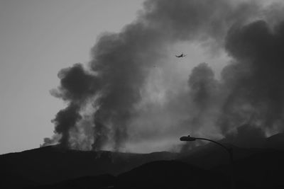 Low angle view of silhouette airplane flying in wildfire 