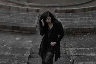 Young woman standing against staircase