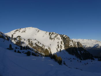 Scenic view of snowcapped mountains against clear blue sky