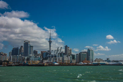 Sea by modern buildings against sky in city