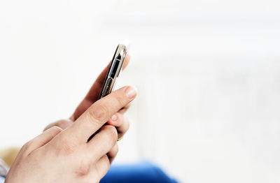 Close-up of hand holding smart phone over white background